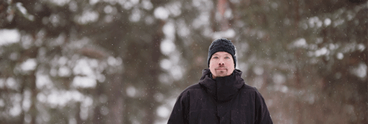 Joonas Rapila seisoo ulkona, taustalla luminen mets&#228;.