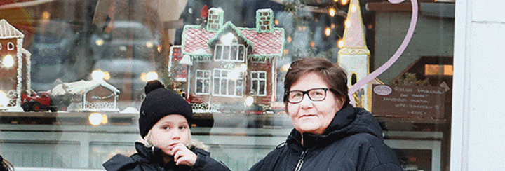 Irmeli Toivanen seisoo kahvilan ulkopuolella lapsenlapsensa kanssa.